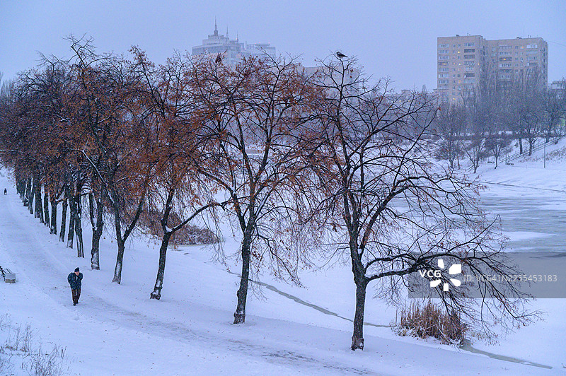 冬日城市公园里，一个人走在雪道上图片素材