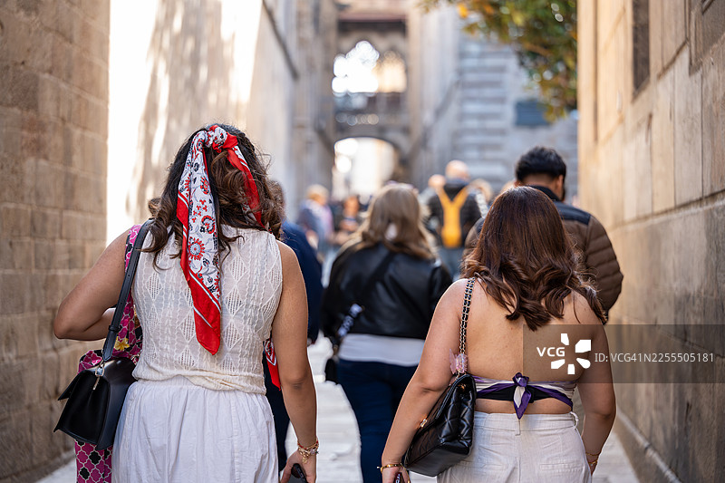 女性游客在巴塞罗那哥特区一条狭窄的街道上探索图片素材