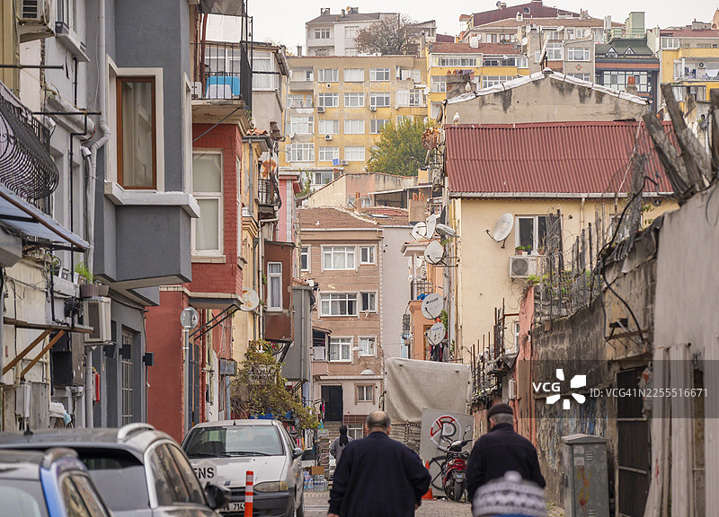 人们走在伊斯坦布尔巴拉特区的街道上，周围是住宅楼图片素材