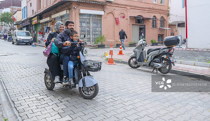 土耳其家庭在城市街道骑行电动三轮车图片素材