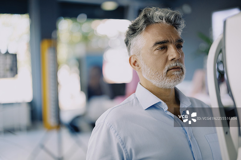 一位男士在现代验光诊所的视力测试机前进行眼科检查。图片素材