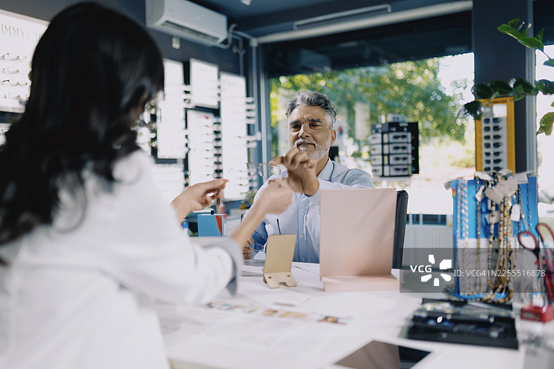一位女性眼科医生在现代眼科诊所帮助患者挑选眼镜架。图片素材