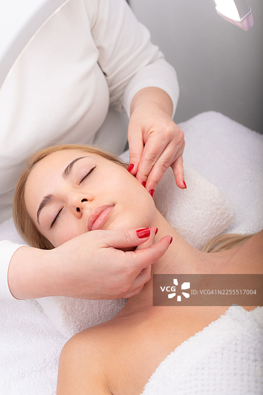 年轻女子在美容水疗中心接受面部按摩图片素材