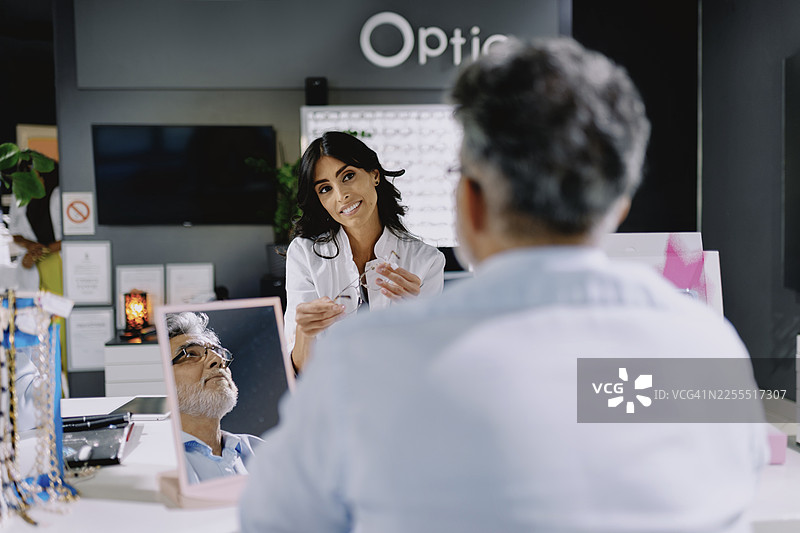 一位女性眼科医生正在现代化的眼科诊所帮助患者挑选镜框。图片素材