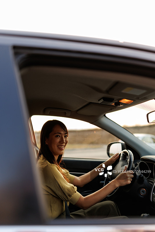 亚洲女性在驾车途中享受金色时段的阳光图片素材