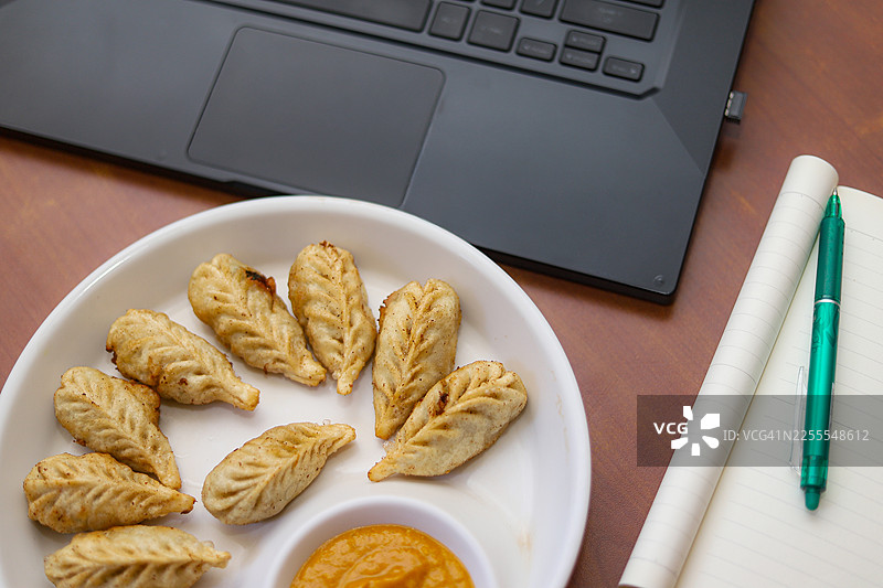 居家办公 - 边吃边工作 - 饺子、笔记本电脑、钢笔和日记本图片素材