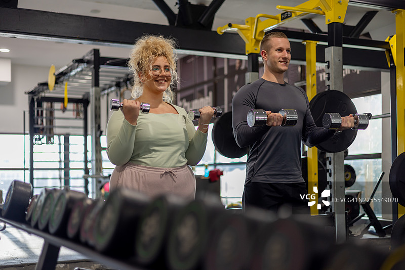 胖女人在健身房与教练一起锻炼图片素材
