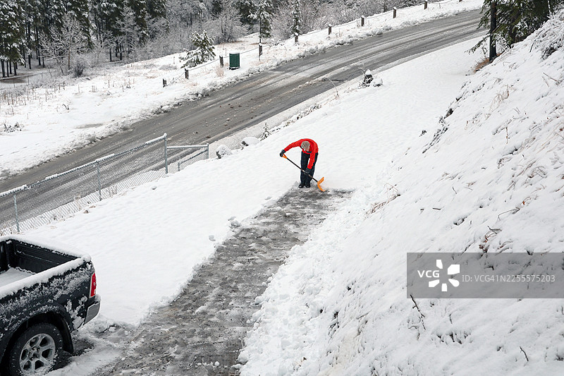 俯视角度拍摄的成熟男性正在清理车道上的积雪图片素材