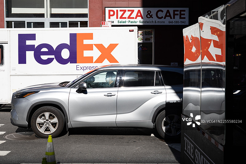 一辆联邦快递货车和一辆银色SUV停在繁忙的纽约曼哈顿街道上图片素材