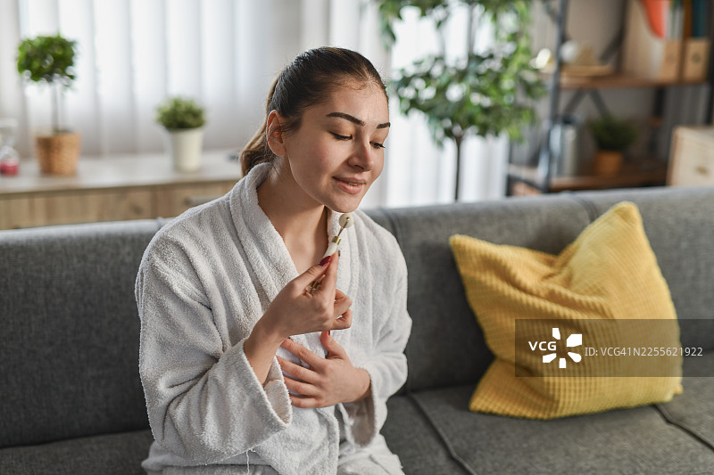 居家水疗时刻：女子使用面部滚轮进行护肤图片素材