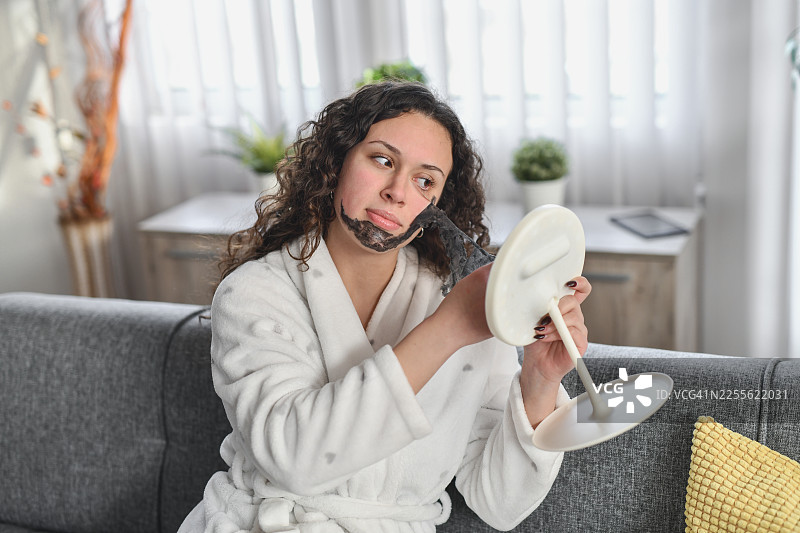 女子在家取下面膜，悠闲地躺在沙发上图片素材