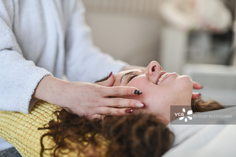 身穿白色浴袍的女子正在接受舒缓的水疗面部按摩图片素材
