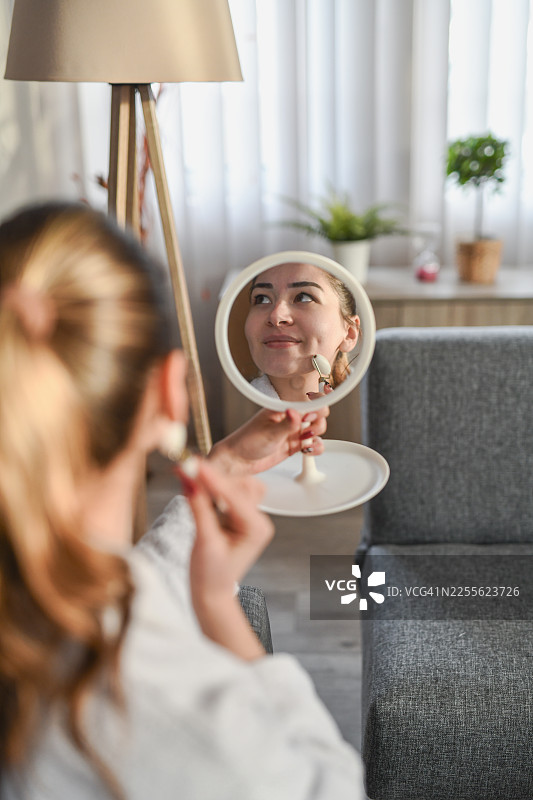 女性在进行护肤时的放松状态，倒映在圆形镜子中图片素材