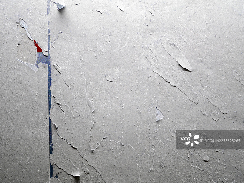 白色、蓝色和红色的纸张贴在墙上，有撕裂和剥落的痕迹。粗糙的纹理。法国巴黎。图片素材