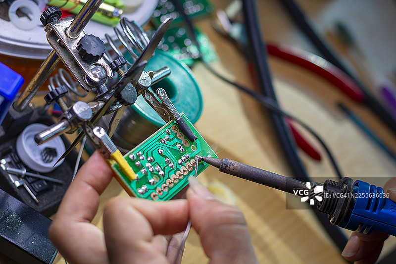 戴着蓝色手套的手在印刷电路板的生产背景上拿着一块PCB芯片组件图片素材