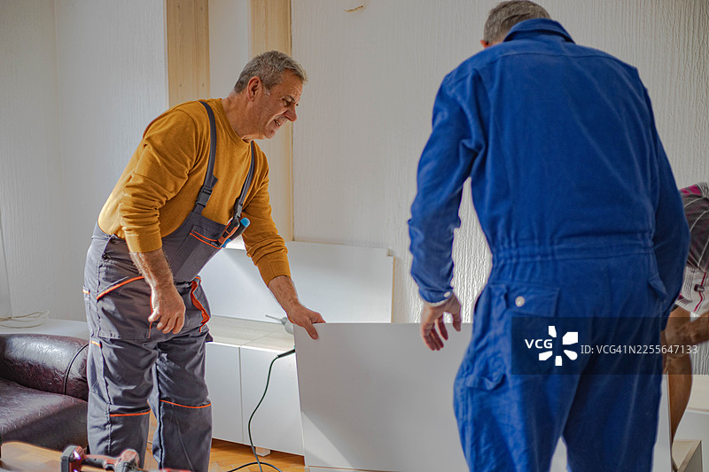在公寓里放置家具，木匠们正在组装架子图片素材