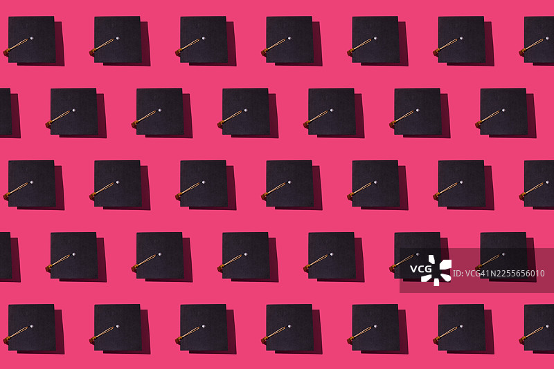 粉色背景上带有金色流苏的黑色毕业帽图案。毕业，粉色，成就，目标，学位，硕士学位，学士学位，大学，学院和成功。图片素材