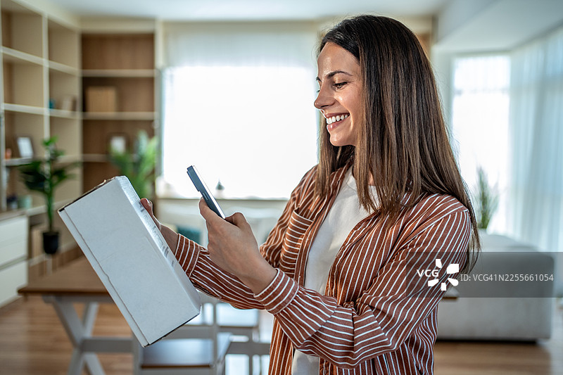 女子用智能手机扫描快递包裹上的条形码图片素材