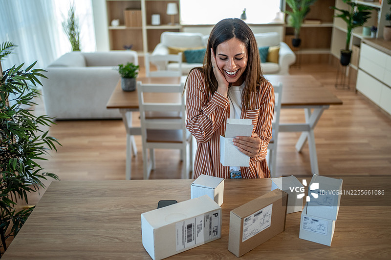 快乐的女人在家拆开网购包裹图片素材