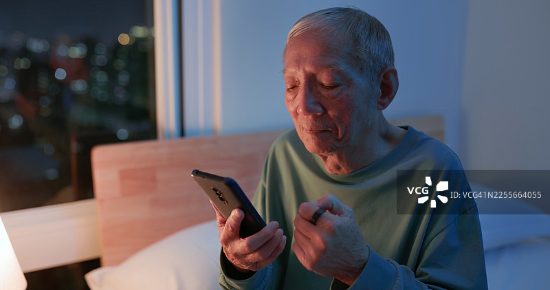 亚洲老年人使用智能手机和智能戒指图片素材