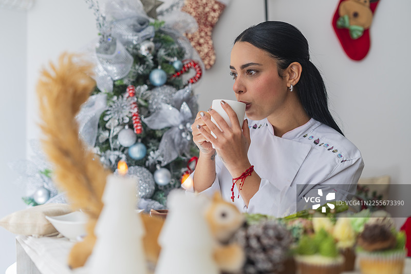 厨师在为她受雇的庆祝活动做准备时，抽出片刻时间享用一杯咖啡。图片素材