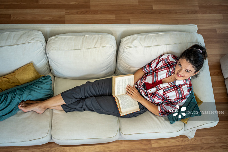 年轻女子在家中沙发上放松阅读图片素材