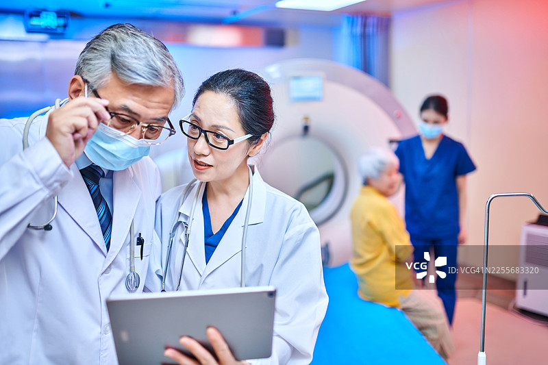 亚洲医生在核磁共振扫描室使用数字平板电脑进行讨论的特写图片素材