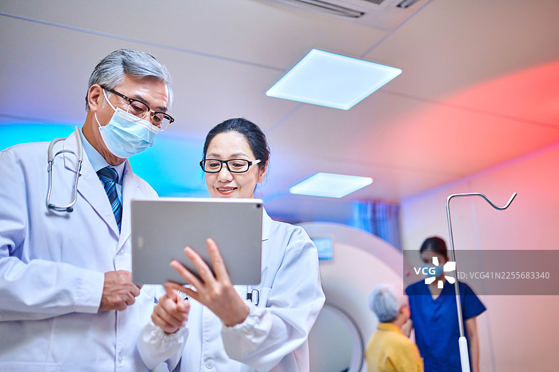 低角度视角，一名亚洲医生在MRI扫描室使用数字平板电脑进行讨论图片素材
