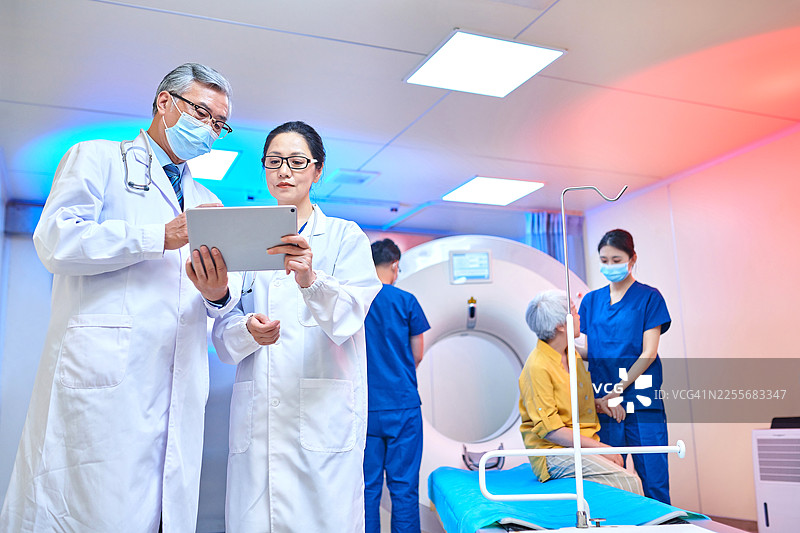 亚洲医生在核磁共振扫描室使用数字平板电脑进行讨论的侧视图图片素材