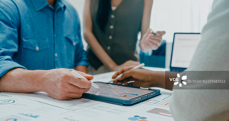 办公室里，多元化的金融团队围坐开会，特写镜头展示他们正在讨论投资策略，并在笔记本电脑上展示财务报告。营销策略分析，金融咨询概念。图片素材