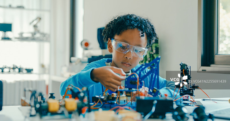 一名非洲裔男孩在家中通过组装机器人进行STEM教育。STEM教育机器人在线课程。图片素材
