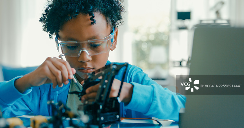 近距离拍摄一名年轻的非裔美国男孩在家中组装机器人，进行STEM教育。STEM教育机器人在线课程。图片素材