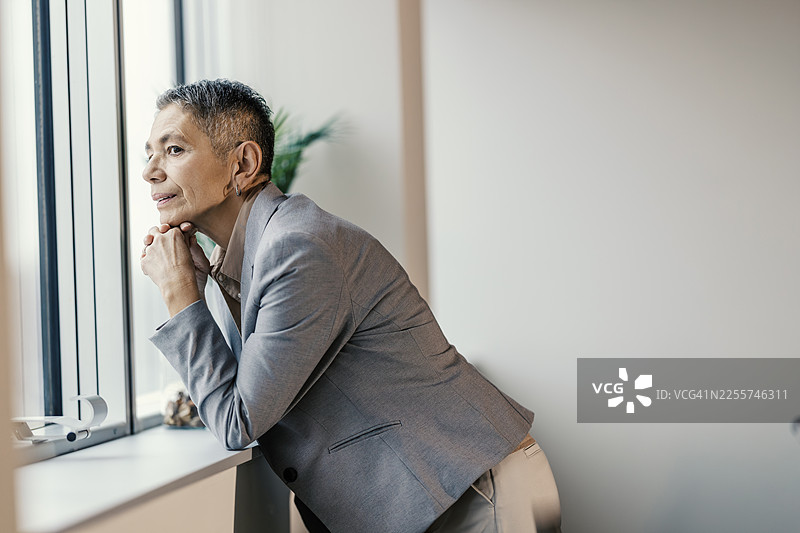 一位成熟的女商人正在办公室的窗前沉思未来图片素材