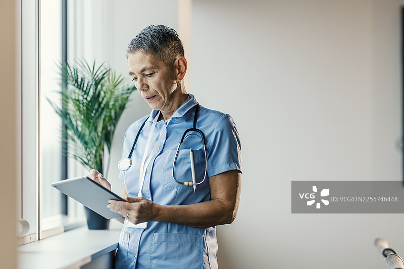 经验丰富的护士在诊所使用平板电脑工作图片素材