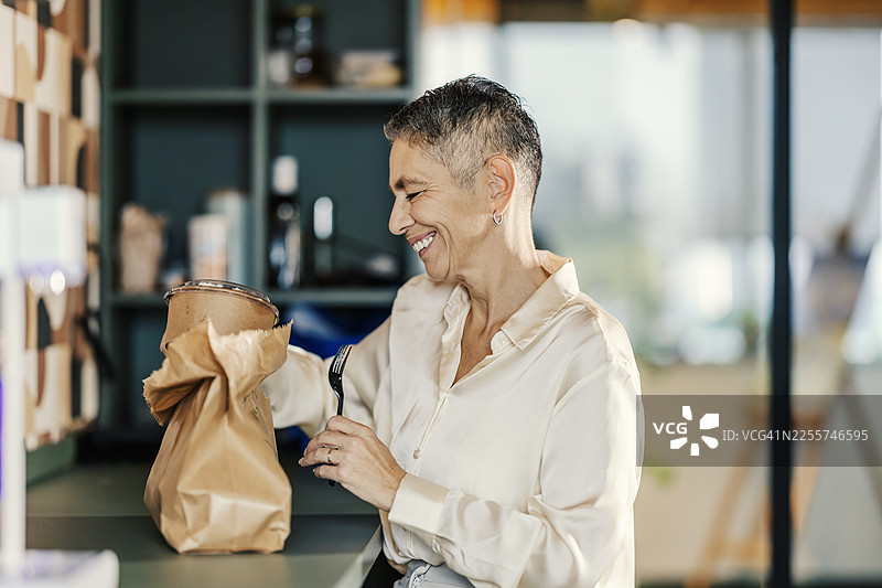 快乐的中年女性享受外卖午餐休息时间图片素材