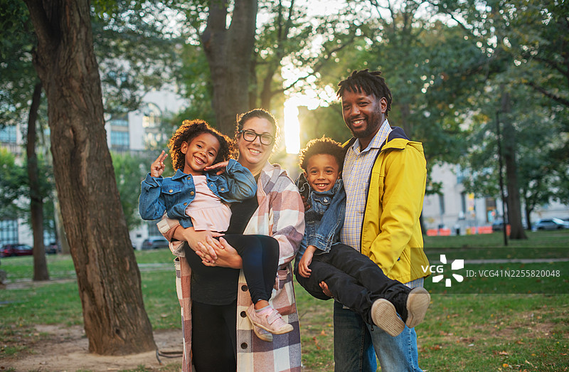秋季黄金时段，现代混血家庭在新泽西州纽瓦克市的城市公园里合影图片素材