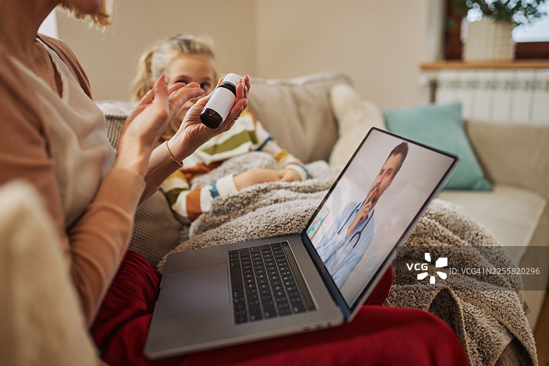 母亲和孩子在家中通过视频通话接受医生关于疾病护理和安抚的咨询图片素材