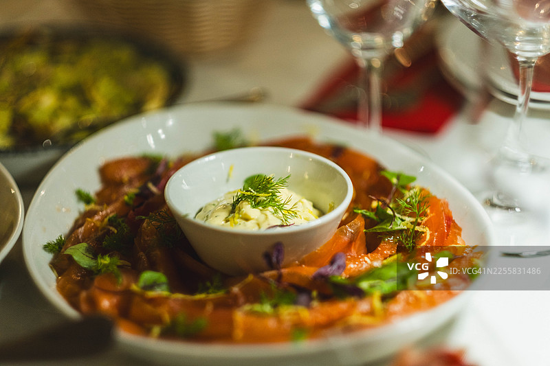 盘中盛着腌制三文鱼，中间放着一碗白酱图片素材