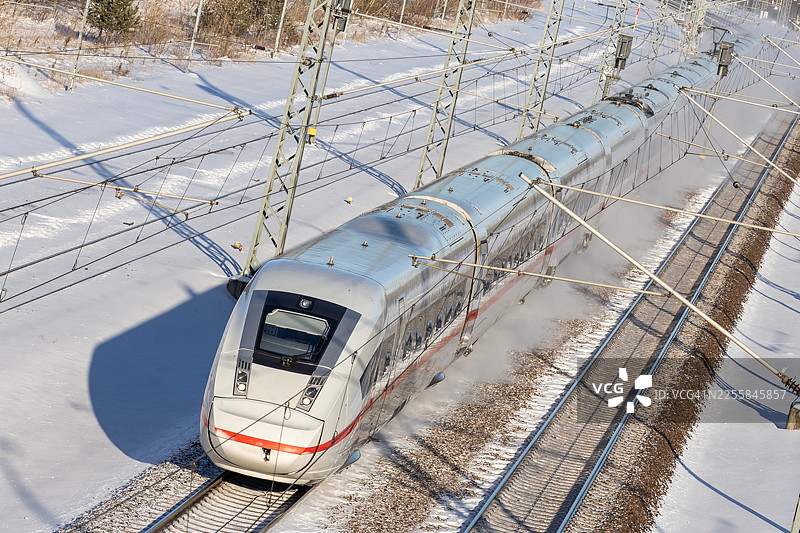 在冬季雪景中，德国高速列车ICE（城际快车）在雪雾中高速飞驰的铁轨图片素材