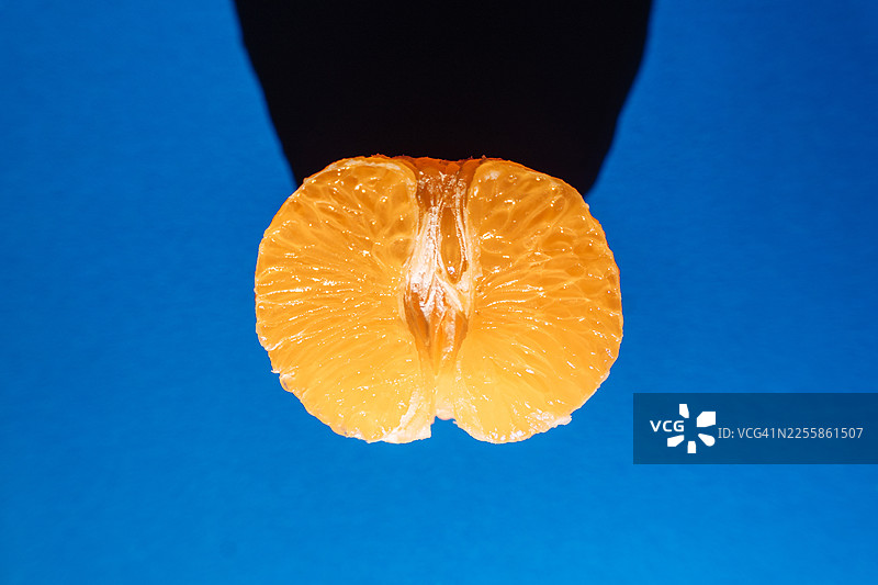 蓝底阴影下的半个橘子图片素材
