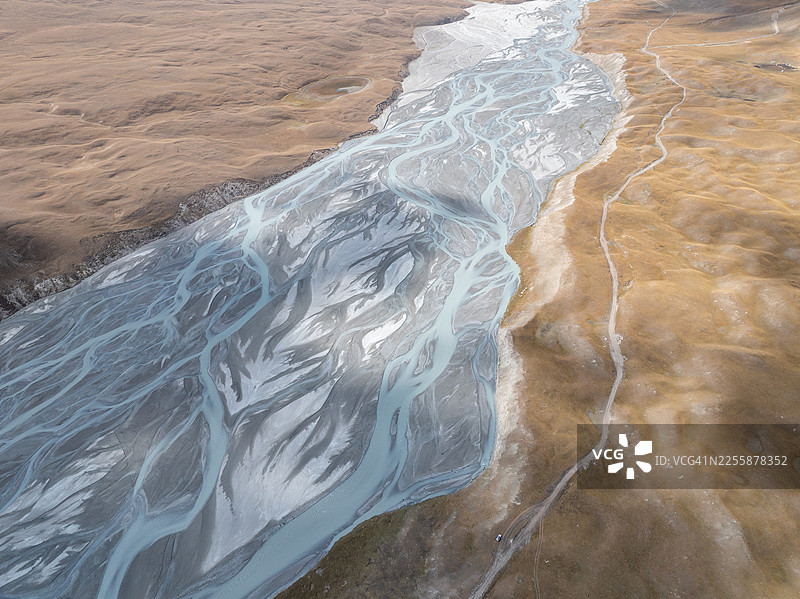 吉尔吉斯斯坦天山山脉高海拔金色高原上，蜿蜒曲折的冰川河流形成的抽象空中图案图片素材