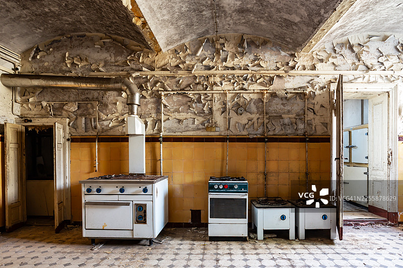 废弃建筑的老厨房里，两扇门之间有四排炉灶图片素材
