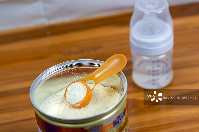 浅色背景下特写奶粉和蓝色勺子。罐子里的婴儿奶粉和量勺。婴儿用奶粉和勺子。婴儿奶粉和奶瓶图片素材