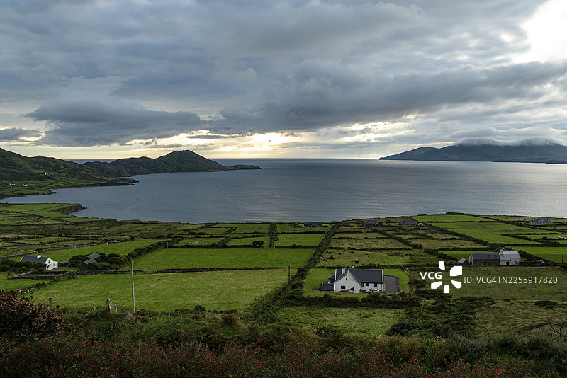从空中俯瞰，绿色的草地被天然石墙和典型的乡村小屋环绕，远眺大西洋和巴林斯凯利格斯湾，靠近沃特维尔，凯里环线，伊弗里半岛，凯里郡，爱尔兰图片素材