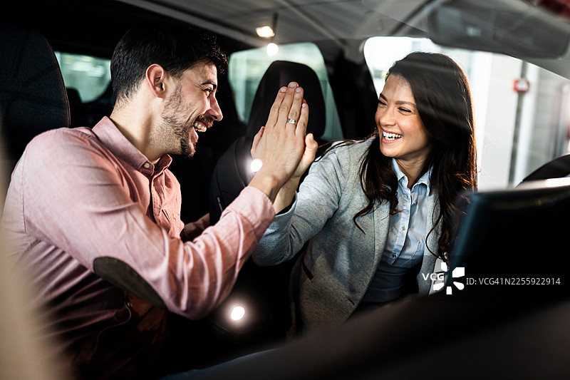 一对幸福的情侣在新车里击掌庆祝图片素材