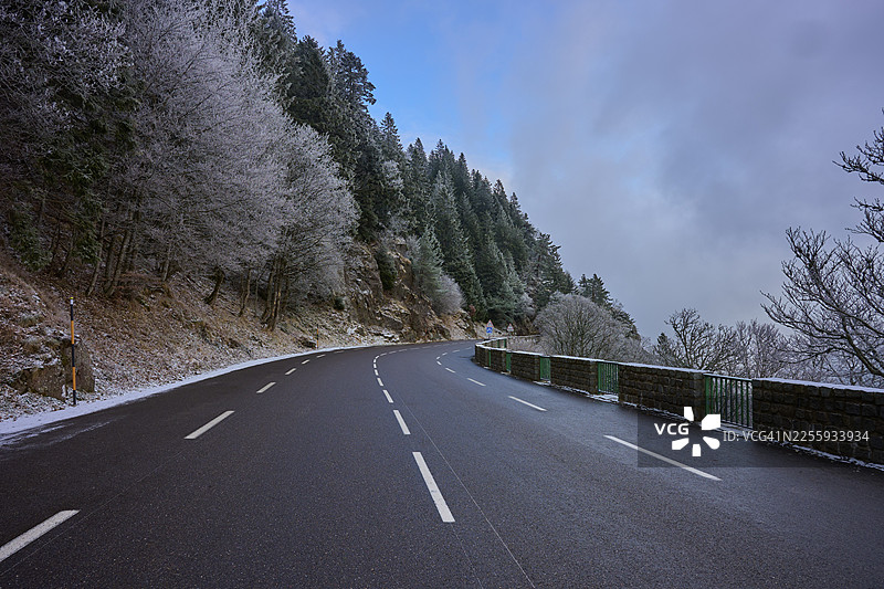 白雪皑皑的道路蜿蜒穿过冬季森林，树木覆满霜花，冬季，法国孚日省勒瓦尔坦科尔德拉施卢赫特图片素材