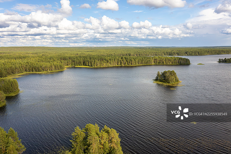 芬兰卡伊努区普奥兰卡，大湖上有小岛，周围是森林，天空多云图片素材