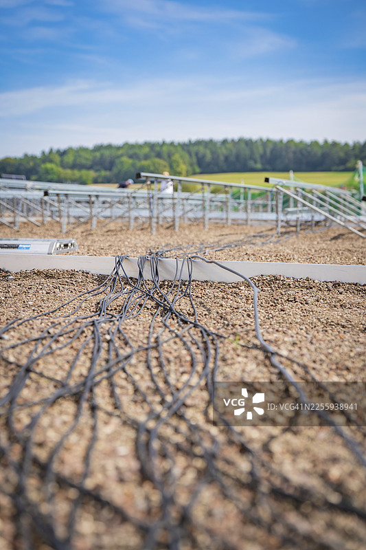 晴朗天空下,铺满碎石的屋顶上铺设着太阳能模块的线缆,位于德国卡尔夫·海马登的赫尔曼·海塞铁路旁新建的停车场和乘车区车库图片素材
