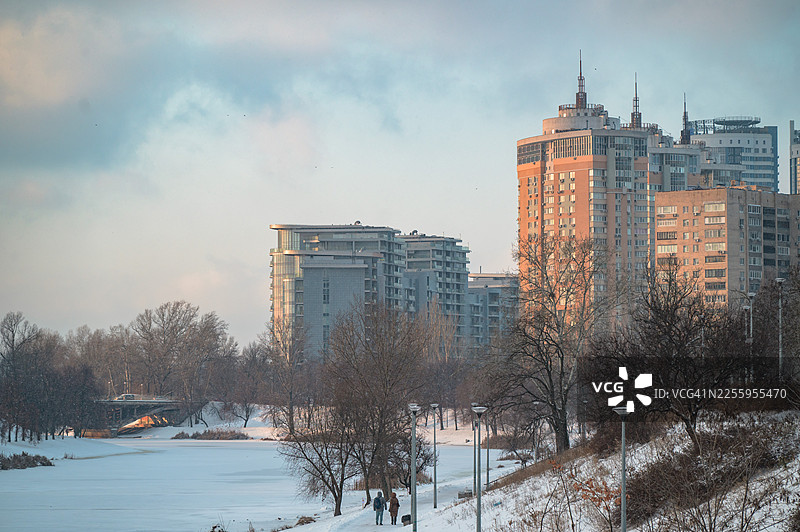 人们在下雪的城市公园里行走，旁边有建筑图片素材