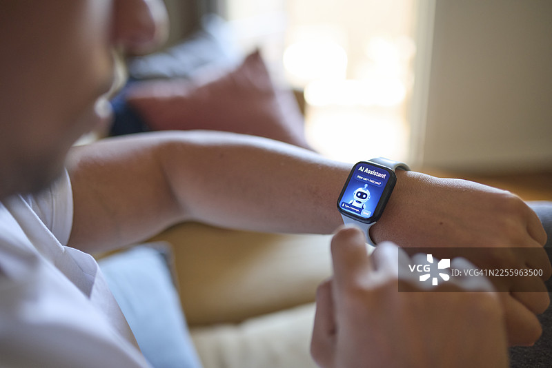 特写：男子坐在沙发上，在智能手表上使用人工智能助手图片素材